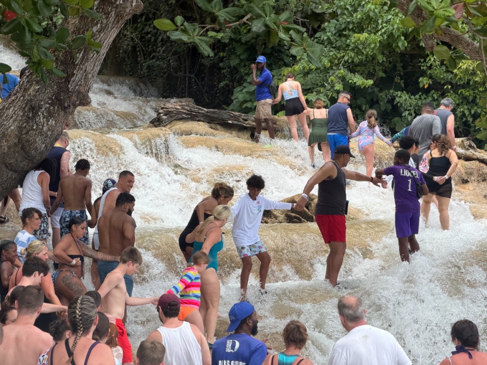 Visitors holding hands while climbing through the rushing water at Dunn’s River Falls
