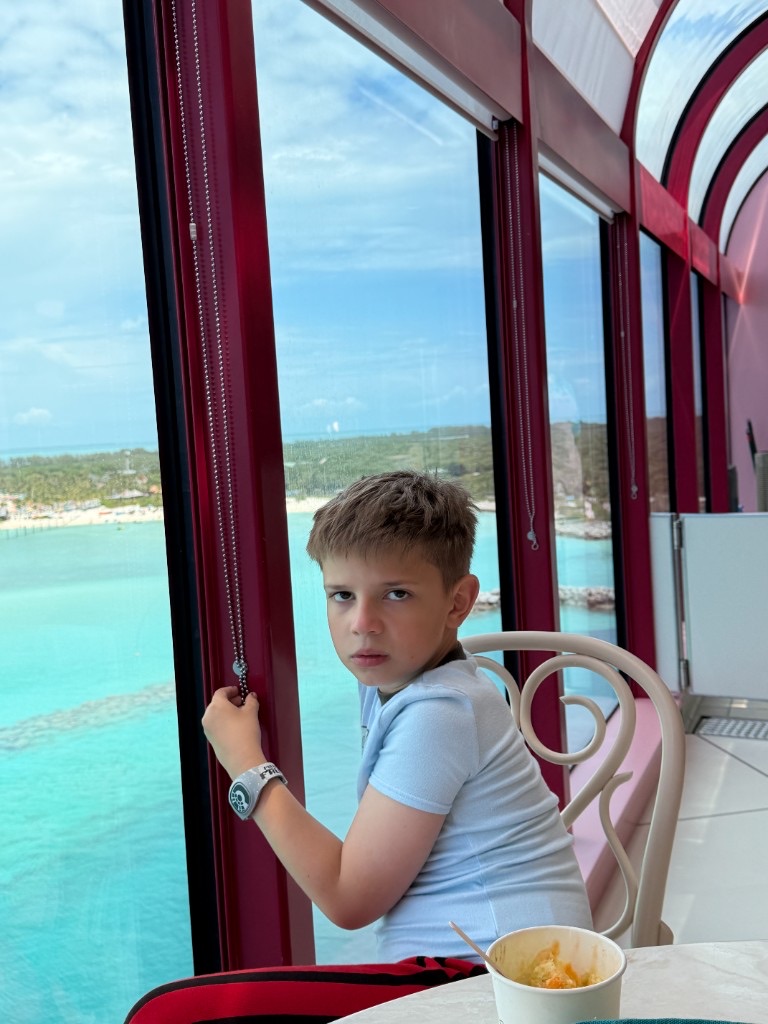 Child at a window-side table overlooking Castaway Cay from the ship