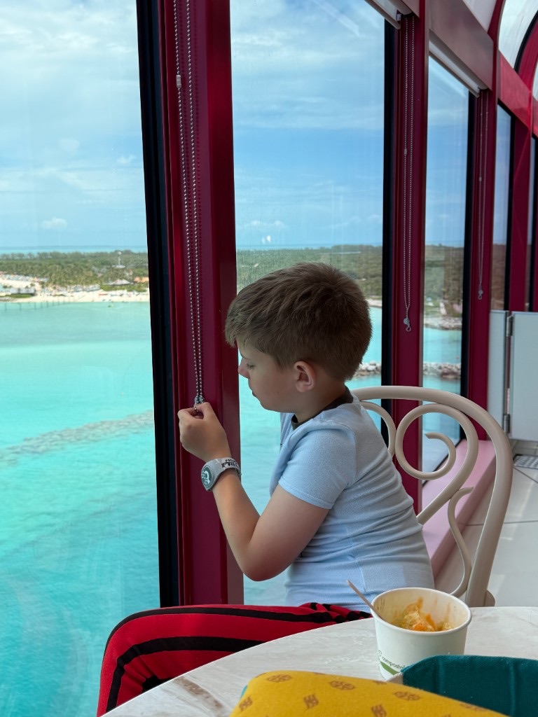 Child looking out at Castaway Cay from a ship window