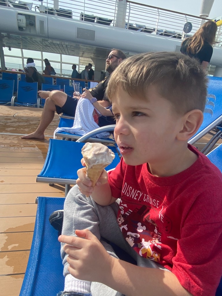 Child eating soft-serve ice cream on the Disney cruise pool deck